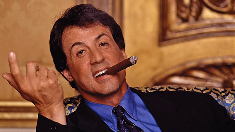 Silvester Stallone smiling and enjoying a cigar