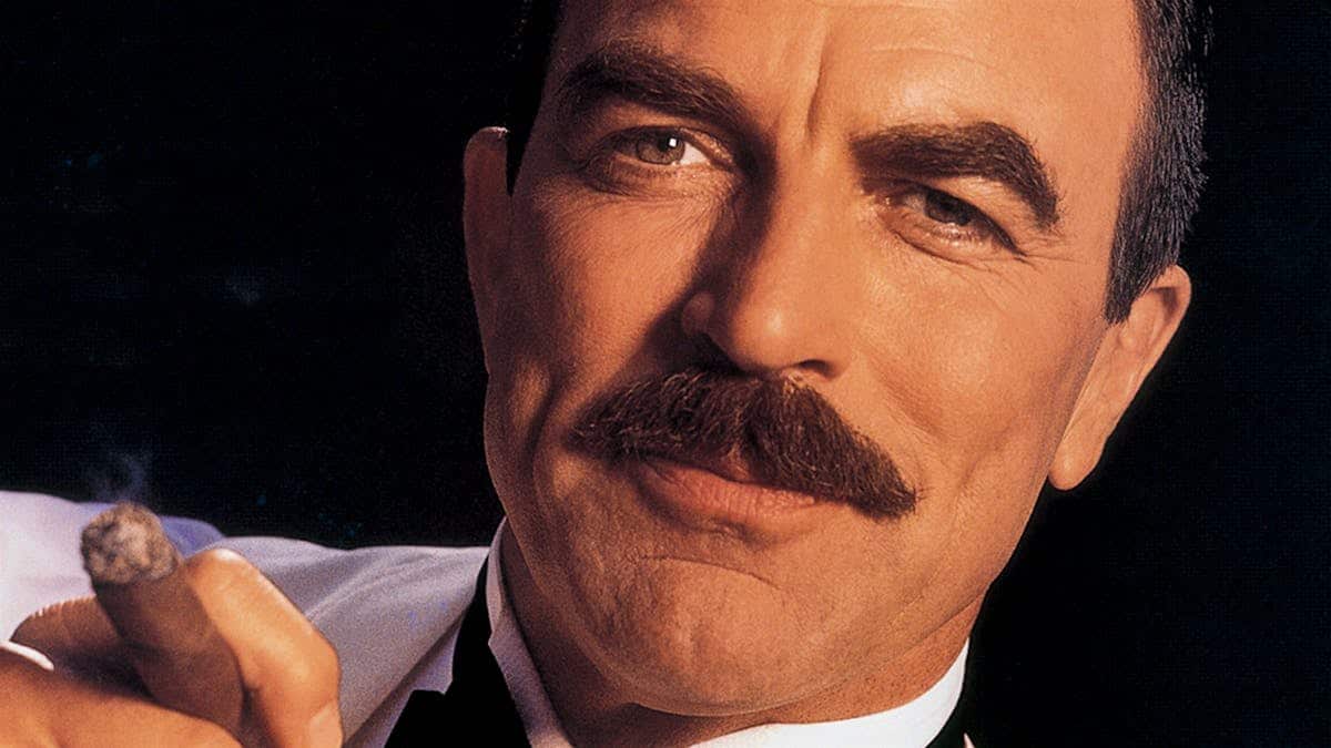 Thomas William Selleck smoking cigar in tuxedo shirt and unbuttoned bow tie